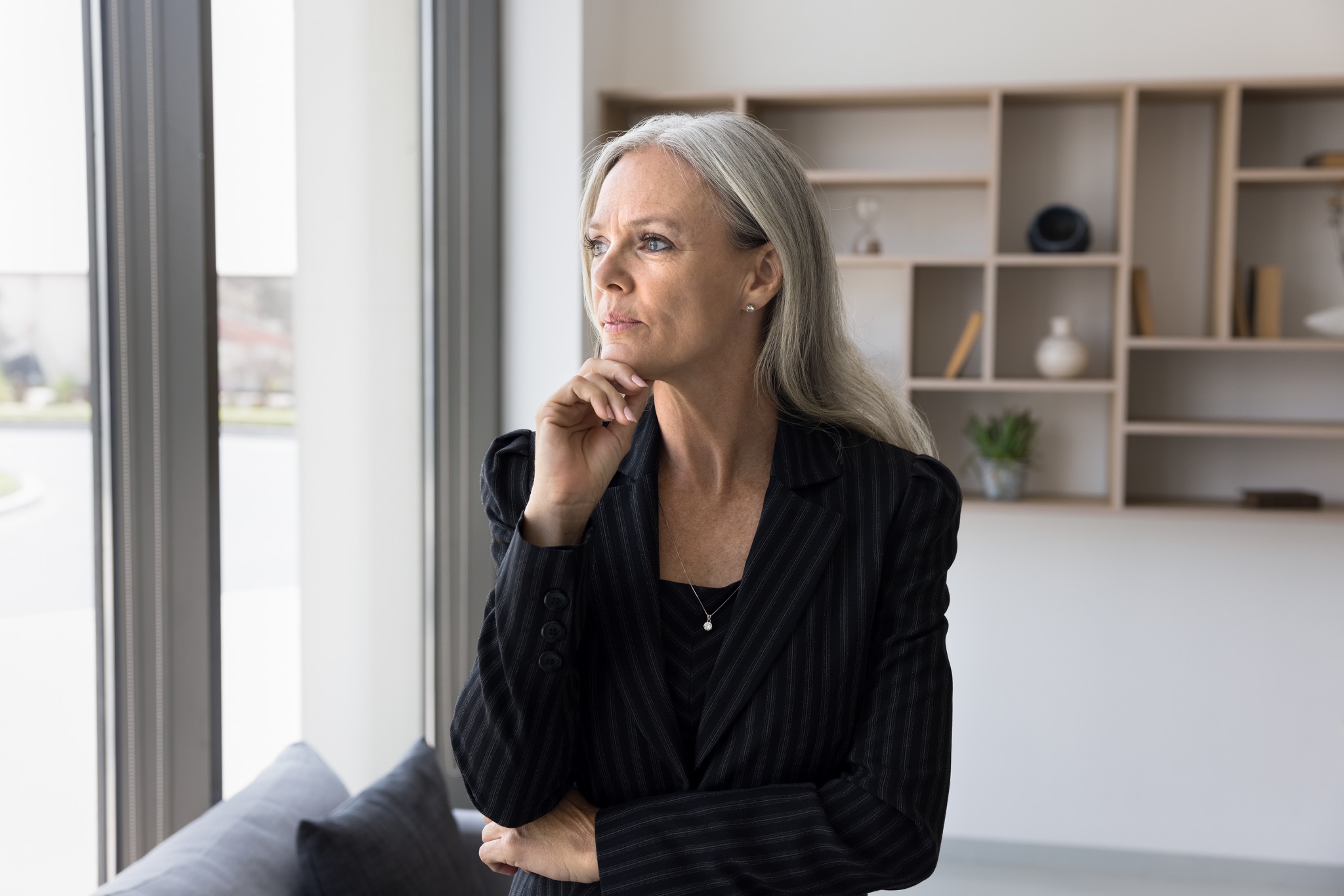 Businesswoman reflecting beside an office window.
